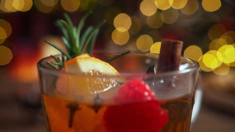 cup of warming winter tea with cloves, orange, anise, rosemary, raspberry and cinnamon stick, christmas mood by the fireplace