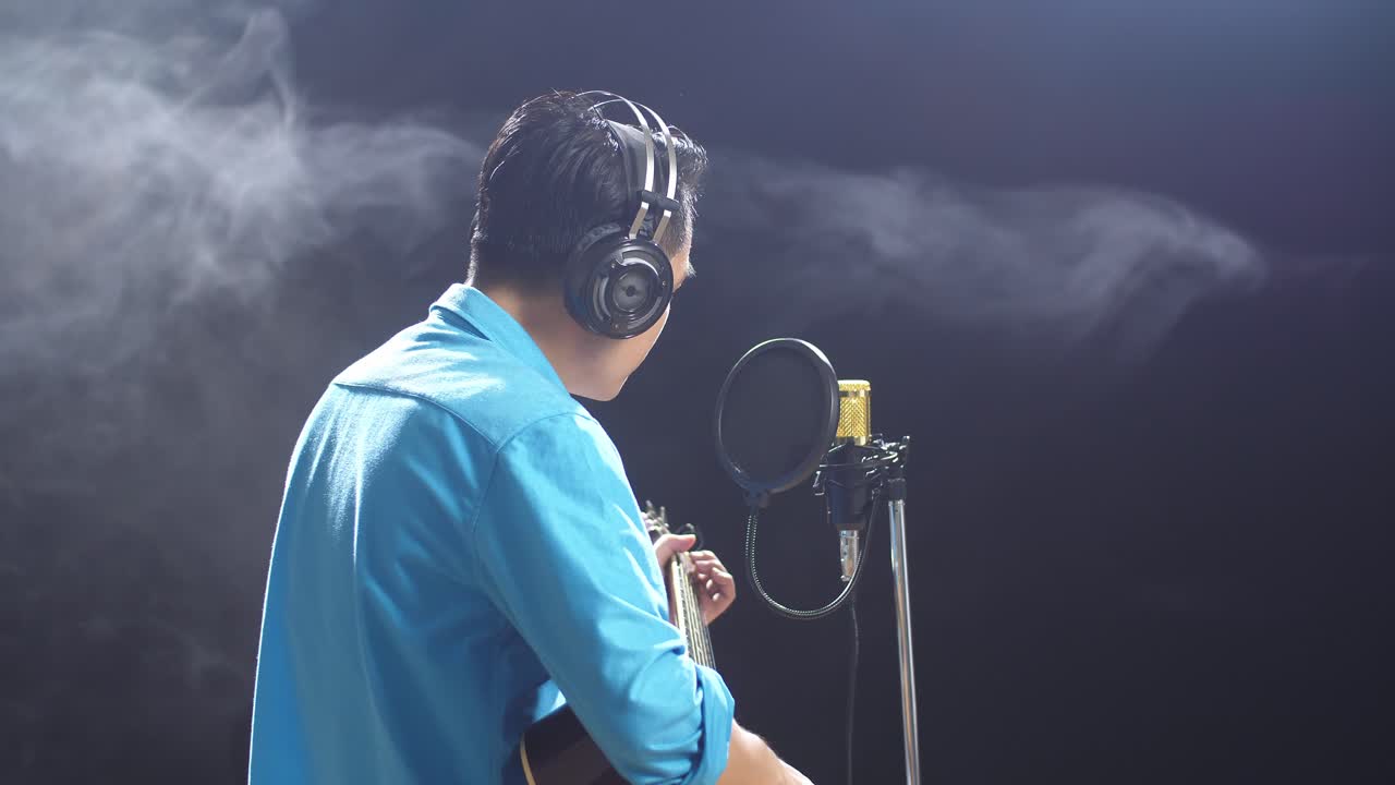 hombre tocando la guitarra acústica en el estudio de grabación