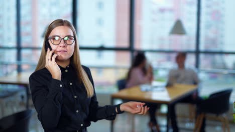 woman in glasses has a conversation on the mobile phone. she ends the talk unsatisfied. female employee dials the number again.