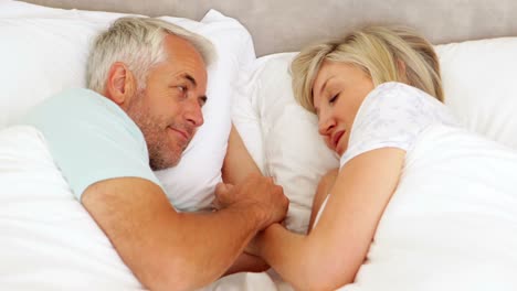 Happy-couple-chatting-and-holding-hands-in-bed