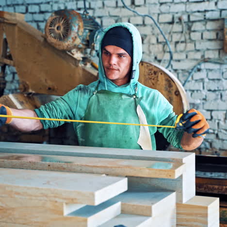 worker with a roulette measuring slabs in the factory. serious man is working with a tape measure on the industrial plant background.