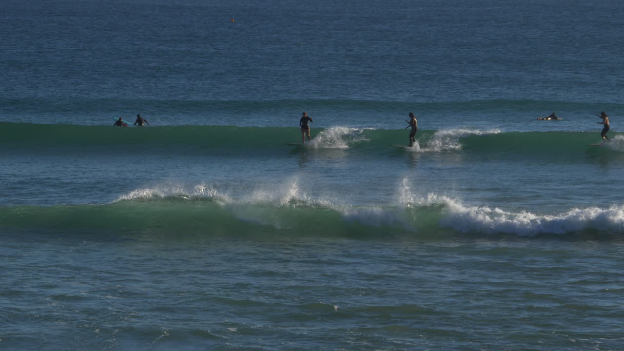 surfistas cabalgando sobre las olas azules en la playa de snapper rocks - aventura de surf en gold coast, queensland, australia - plano general