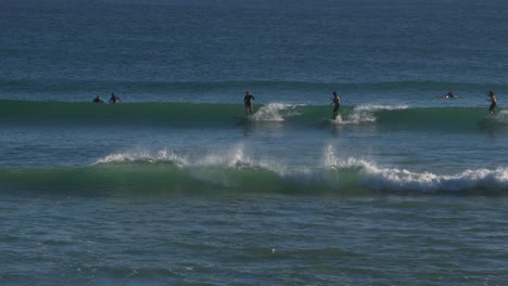 surfers riding on the blue waves in snapper rocks beach - surfing adventure in gold coast, qld, australia - wide shot