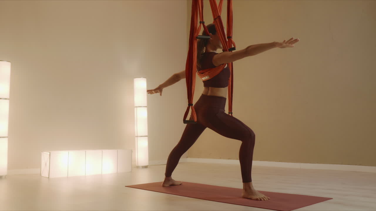 Girl performing yoga with straps in class. Woman doing warrior pose on yoga mat