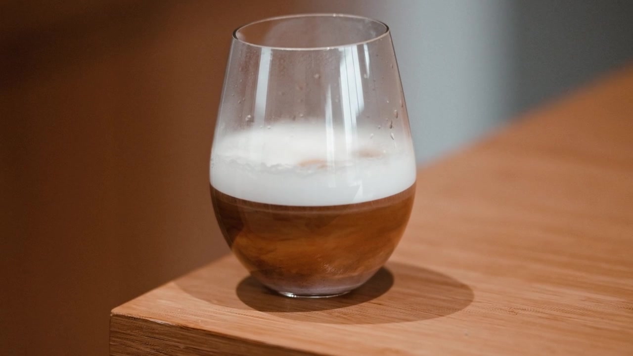 Coffee and frothed milk in a glass on a bamboo counter top