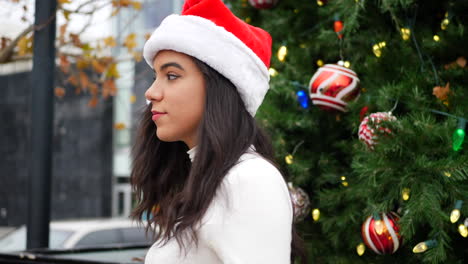 mujer con un sombrero de santa celebrando la feliz temporada navideña con un árbol de navidad, adornos y luces