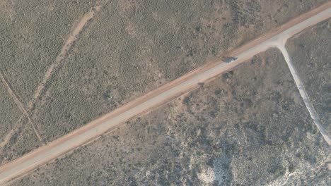 Coche-Conduciendo-Por-Una-Carretera-En-El-Desierto-Australiano-Con-Una-Larga-Sombra-Durante-La-Hora-Dorada-En-Exmouth,-Australia-Occidental