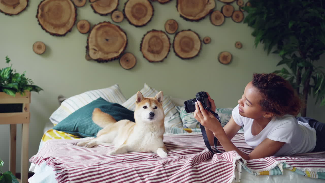 Woman taking photo of her dog on a bed