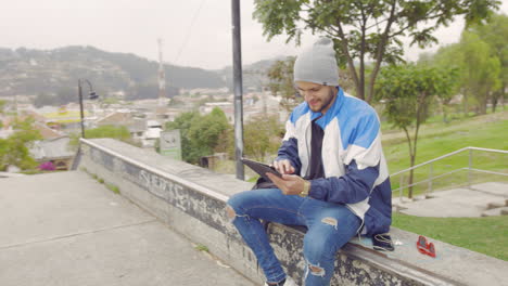 Joven-Usando-Una-Tableta-En-Un-Parque