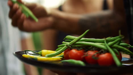 Chef-hands-putting-vegan-food-on-grill-outside.-Plate-with-grilled-vegetables