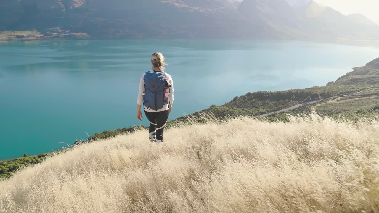 niña caminando en hierba dorada en las montañas de nueva zelanda con vistas al lago azul