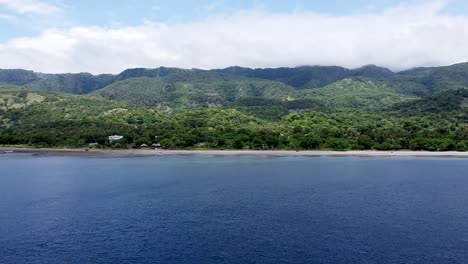 flying towards a rugged, remote and secluded mountainous volcanic tropical island covered in trees, aerial drone of stunning ocean, atauro island, timor leste, southeast asia