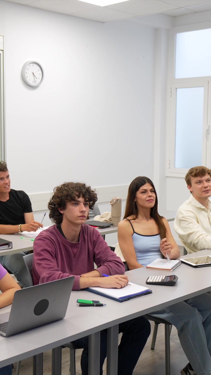 Professore che insegna a giovani adulti in un'aula luminosa.