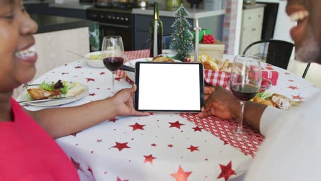 una pareja afroamericana sonriente haciendo una llamada de video de navidad en una tableta, copia el espacio en la pantalla