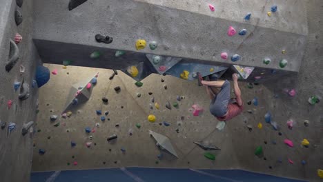 inverted rock climber climbing an indoor rock wall using athletic chalk for grip