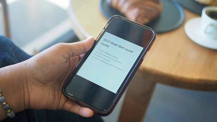 Persona che tiene in mano uno smartphone che mostra gli obiettivi per i social media per il nuovo anno