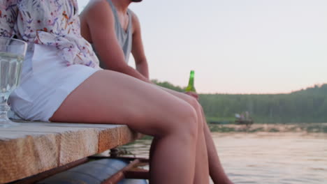 couple chatting on pier and splashing lake water with feet