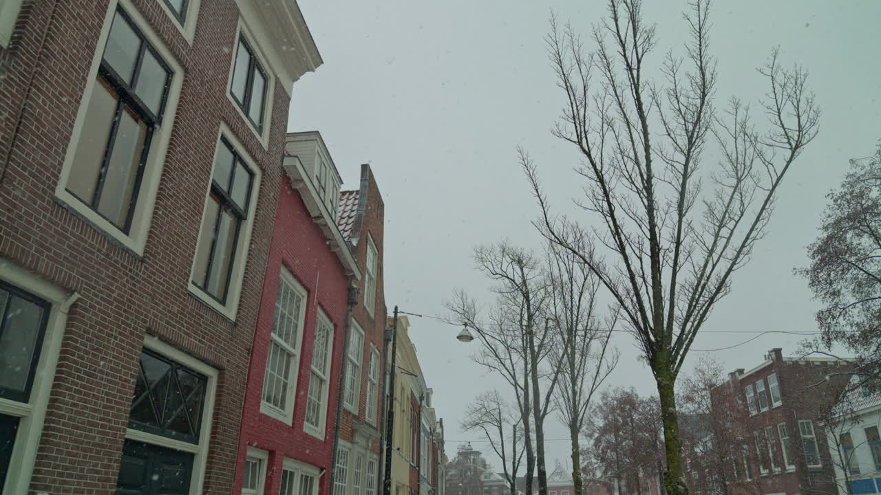 Snefald i en europæisk, hollandsk by i Nederlandene i løbet af vintersæsonen med huse, gader, træer og autentisk nordisk vejr.