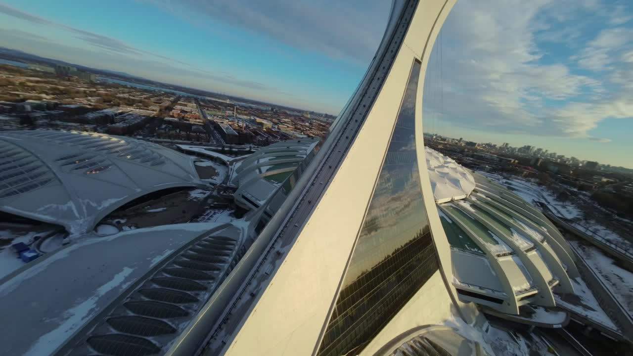 FPV drone flies over Montreal’s snow-covered Olympic Stadium at sunset, winter setting in Canada