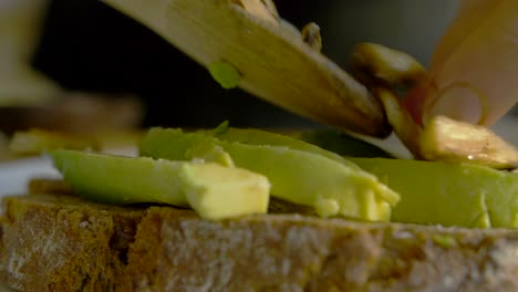 primer plano de una mujer poniendo champiñones en una tostada de aguacate