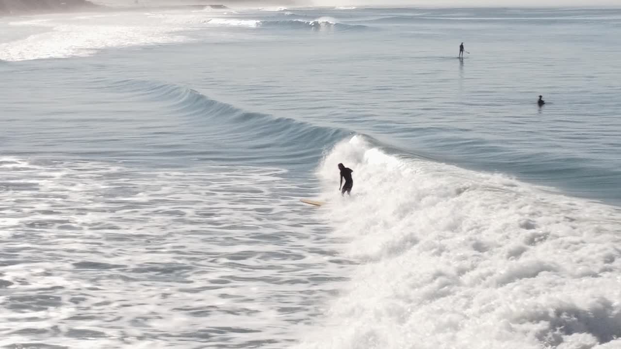 un hermoso disparo aéreo de drones, drones rastreando a un surfista surfeando una ola cerca de la playa, playa estatal de carlsbad - california