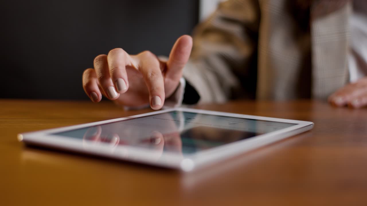 Mano in primo piano che scorre sullo schermo di un tablet su una scrivania