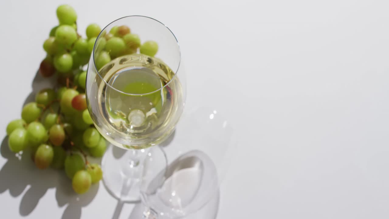 vaso de vino blanco y uvas sobre una superficie blanca con espacio para copiar