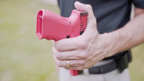 man hand with golden ring holds red gun for training purposes