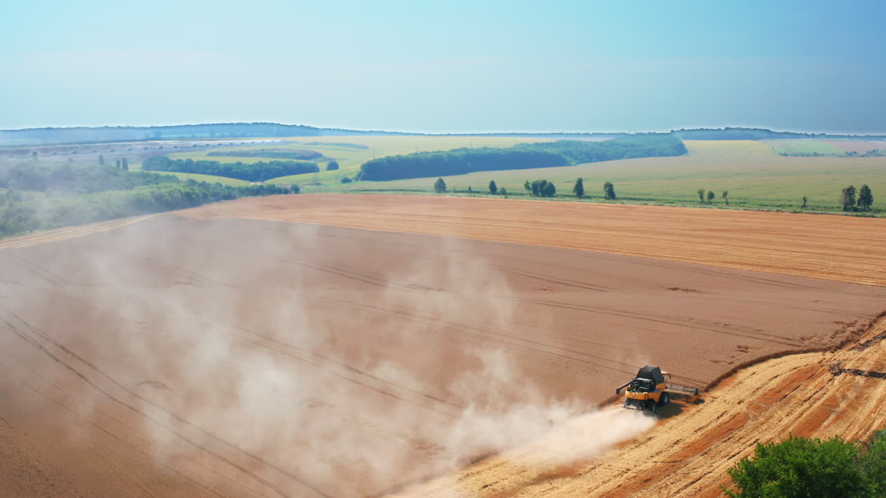 Yellow harvester combine mows the field of wheat. Another machine standing not far away. Top view. Nature backdrop.