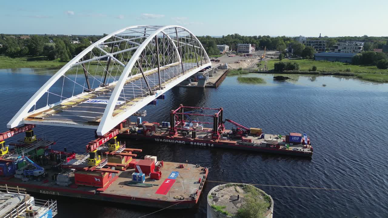Barges install white arch vehicle bridge over river in Parnu, Estonia