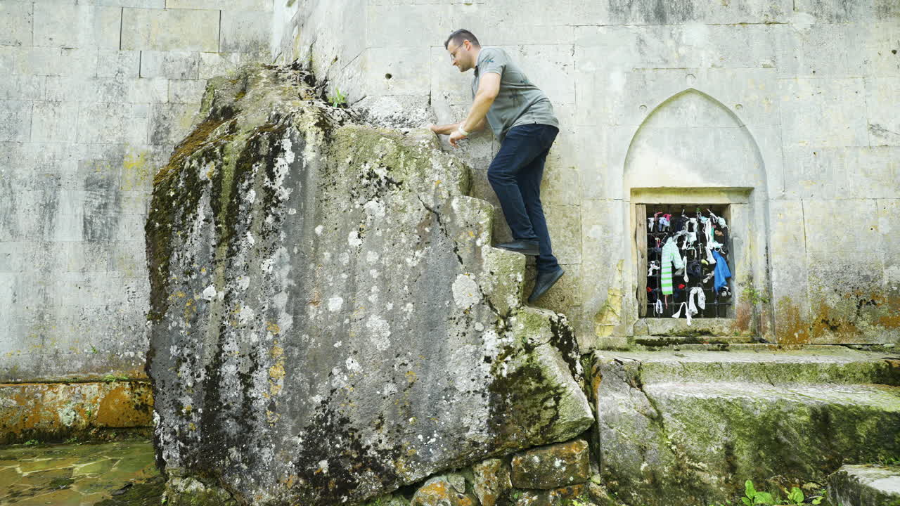 Climbing up the steps of a broken rock-hewn stairs in front of the mausoleum of the Alevian saint Demir Baba Teke, a pilgrimage site in Razgrad province in Bulgaria.