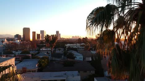 Palm-trees-reveal-a-beautiful,-colorful-sunrise-downtown-Los-Angeles-in-the-horizon