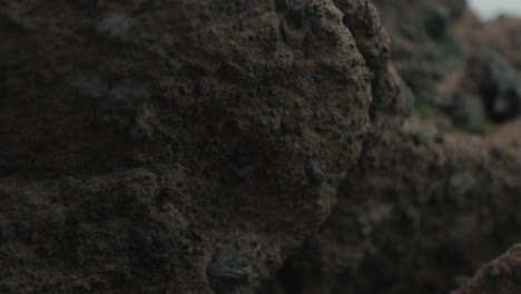 Tilt-down-from-view-of-ocean-to-black-brown-rocks-in-Iceland