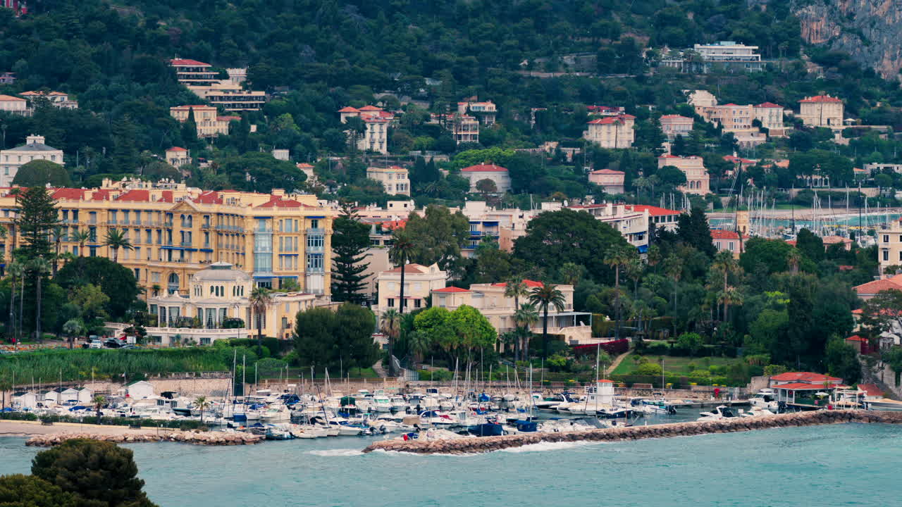 Distant view of boats docked in the harbour with the buildings of Beaulieu-sur-Mer, France on the background