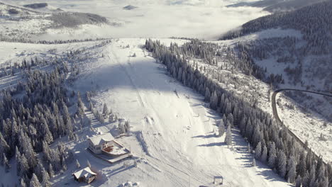 Snow-covered-mountain-landscape-with-pine-trees,-aerial-view-from-Romania,-Rodna-Mountains