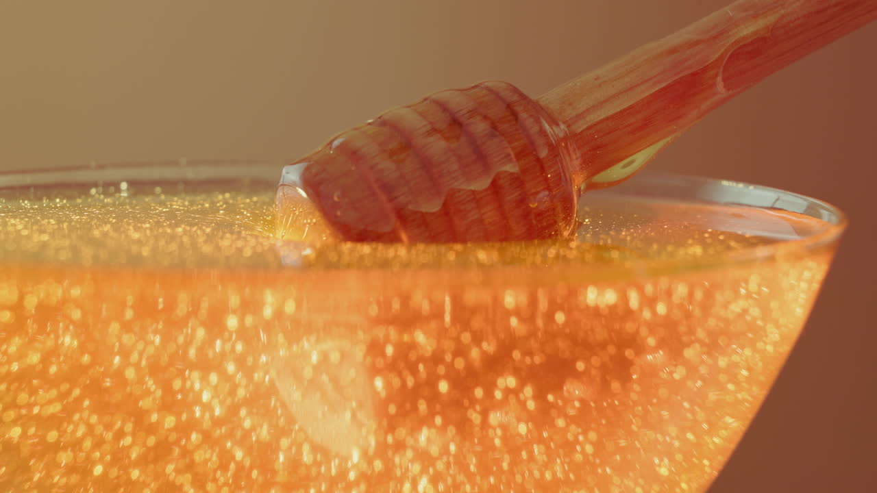 Close-up of honey dripping from a wooden dipper