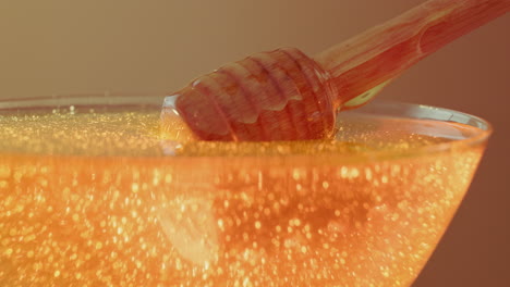 close-up of honey dripping from a wooden dipper