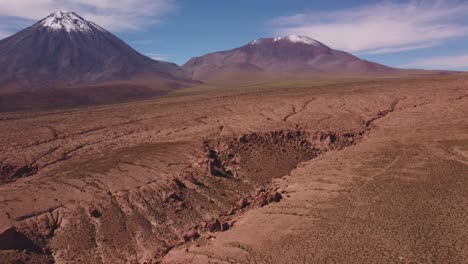 Aerial view of the snow-capped Licancabur Volcano near San Pedro de Atacama, Chile. Cracked desert textures and dramatic Andean highland scenery.