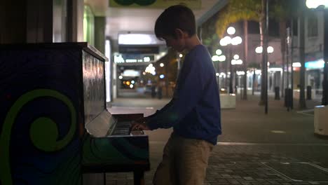 young boy playing piano in the street