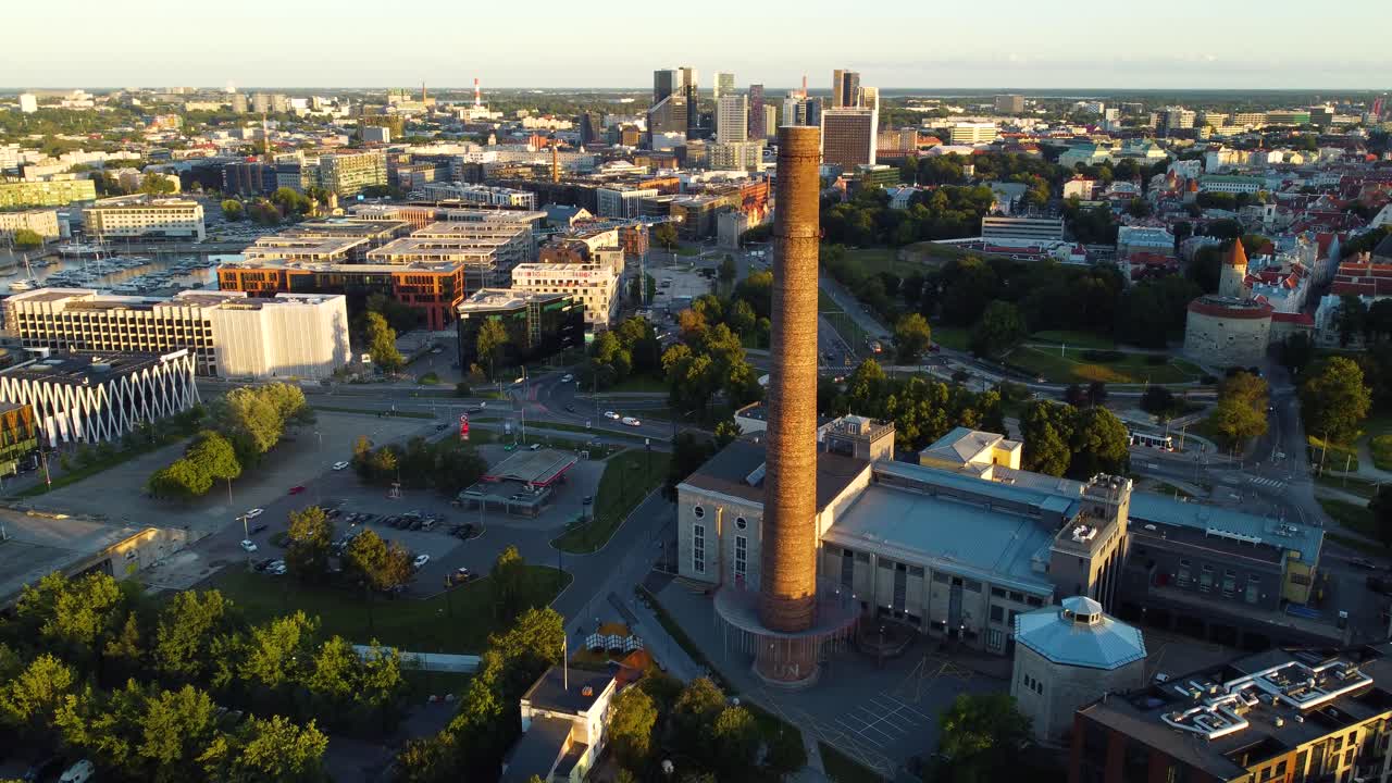 Capturing an expansive aerial view of a modern urban cityscape featuring a prominent industrial chimney amidst buildings and green spaces on a clear day in Tallin Estonia