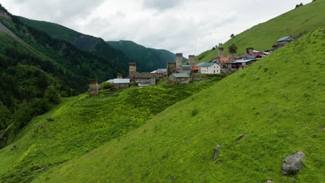 Blick-Auf-Häuser-Und-Antike-Ruinen-Im-Mittelalterlichen-Dorf-Adishi-Auf-üppigem-Hochland-In-Mestia,-Georgia