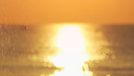 Splash-water-on-stone-surface-on-background-golden-sunset-in-sea