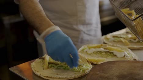 chef adding french fries to chicken shawarma sandwiches