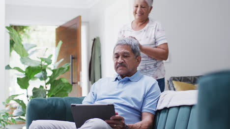 Happy-senior-biracial-couple-with-coffee-using-tablet