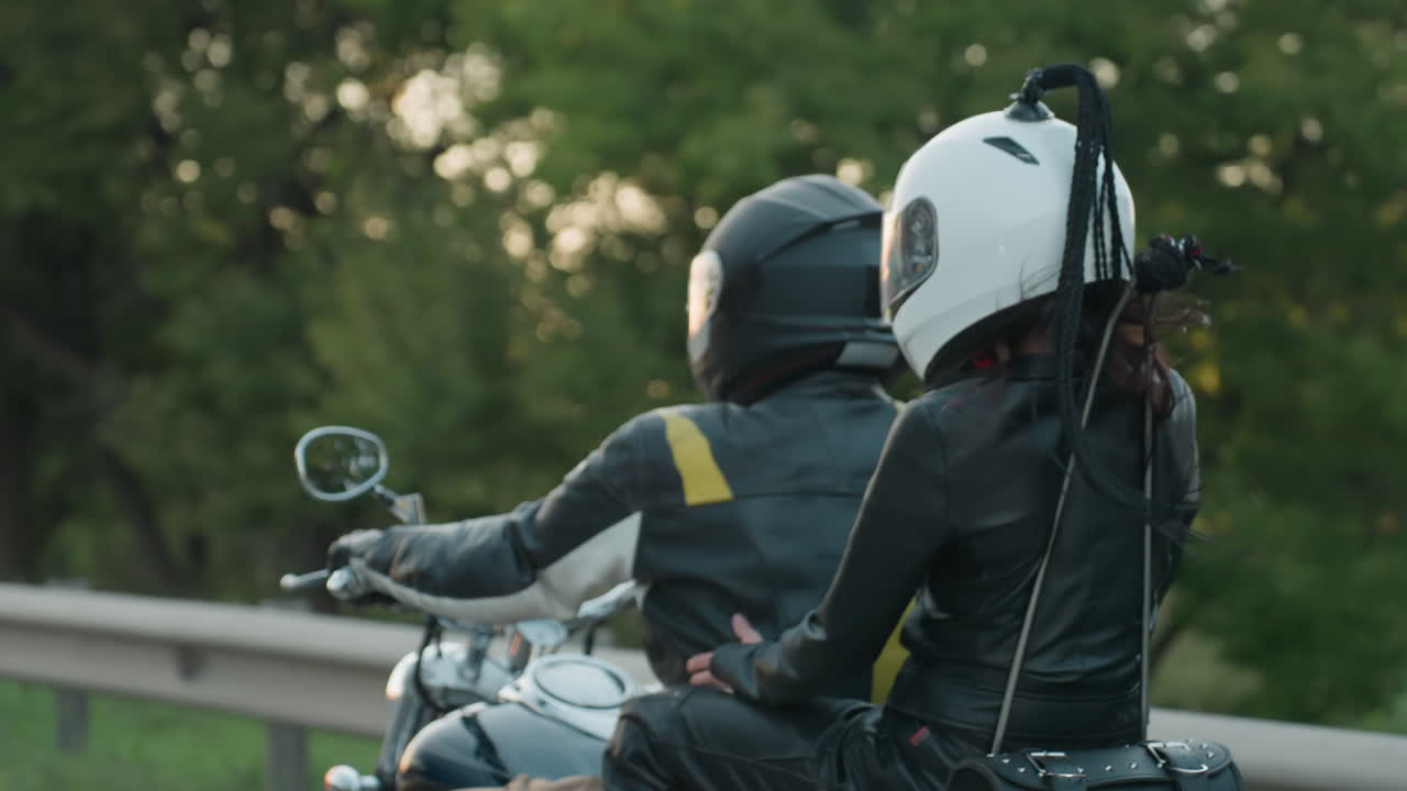 Close up of motorcycle wheel with shiny chrome rim and brake disc rotating on tarred roadside, reflecting movement and power as traveler rides along green grassy edge