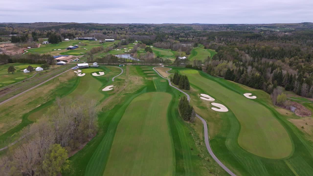 Aerial Establishing shot of well-kept golf course in Alton, Canada. Forest trees in rural suburb district of Toronto. Empty field at cloudy day. Wide shot.