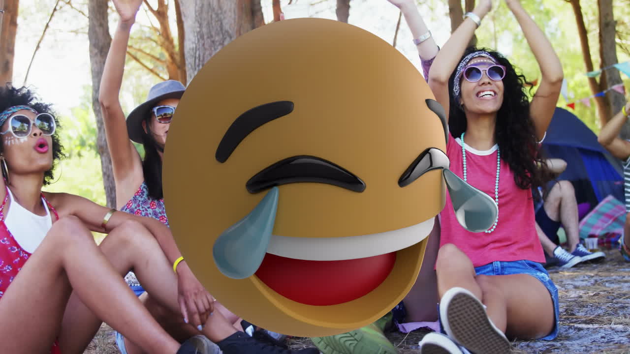 Laughing diverse friends at outdoor gathering using emoji animation for fun