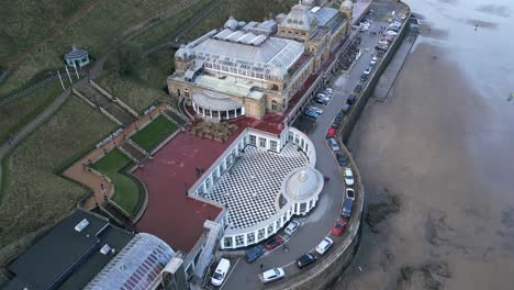 Toma-Aérea-Superior-Del-Spa-De-Scarborough-Con-Algunos-Visitantes-Y-Sus-Autos-Estacionados-Frente-A-él-En-Scarborough,-North-Yorkshire,-Inglaterra