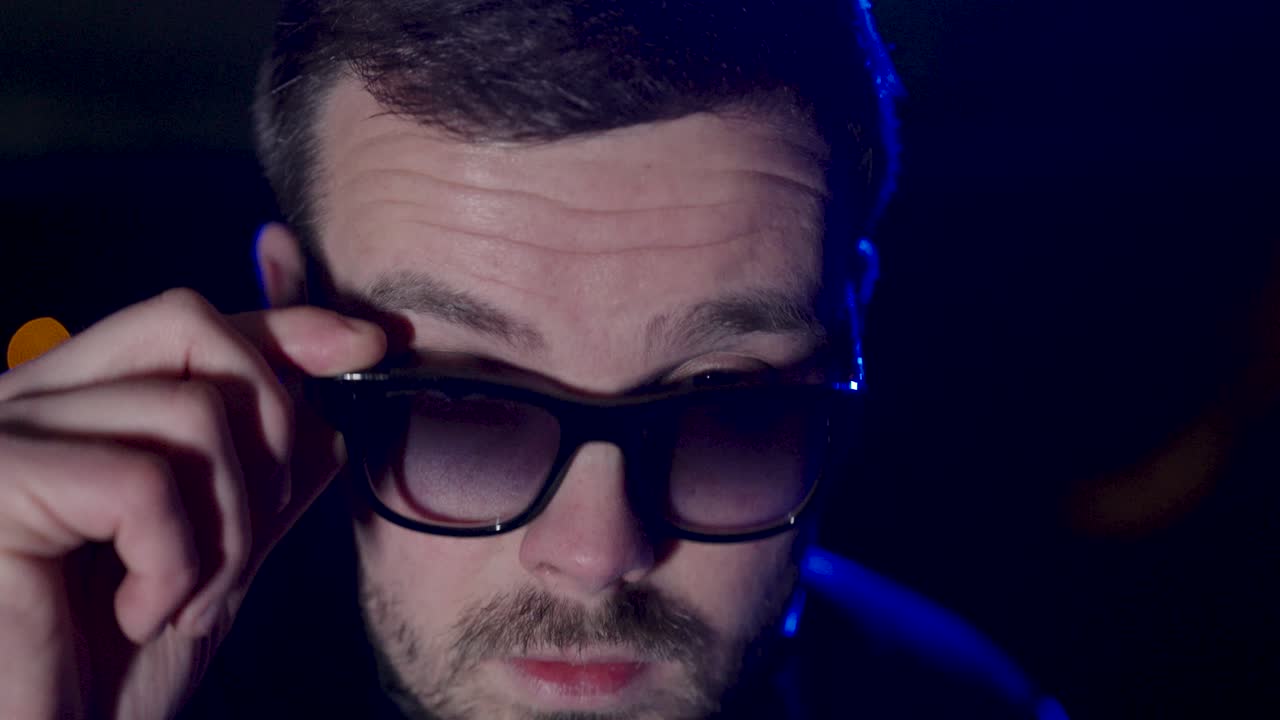 a young man with sunglasses. He pulls his sunglasses down slightly and looks cool. close up