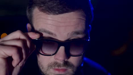 a young man with sunglasses. he pulls his sunglasses down slightly and looks cool. close up